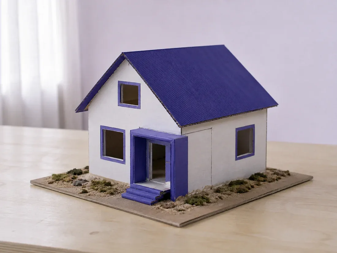 Maqueta de una casa terminada sobre base de cartón, con techo y ventanas recortadas