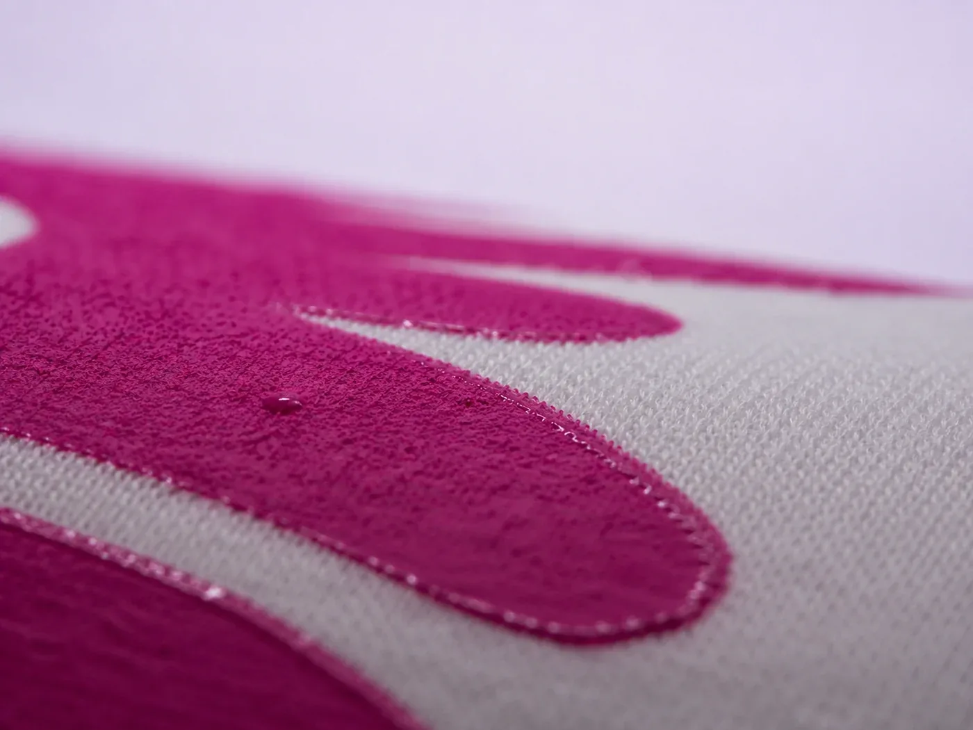 Tinta magenta de serigrafía recién estampada sobre algodón blanco, con la trama de la tela a la vista